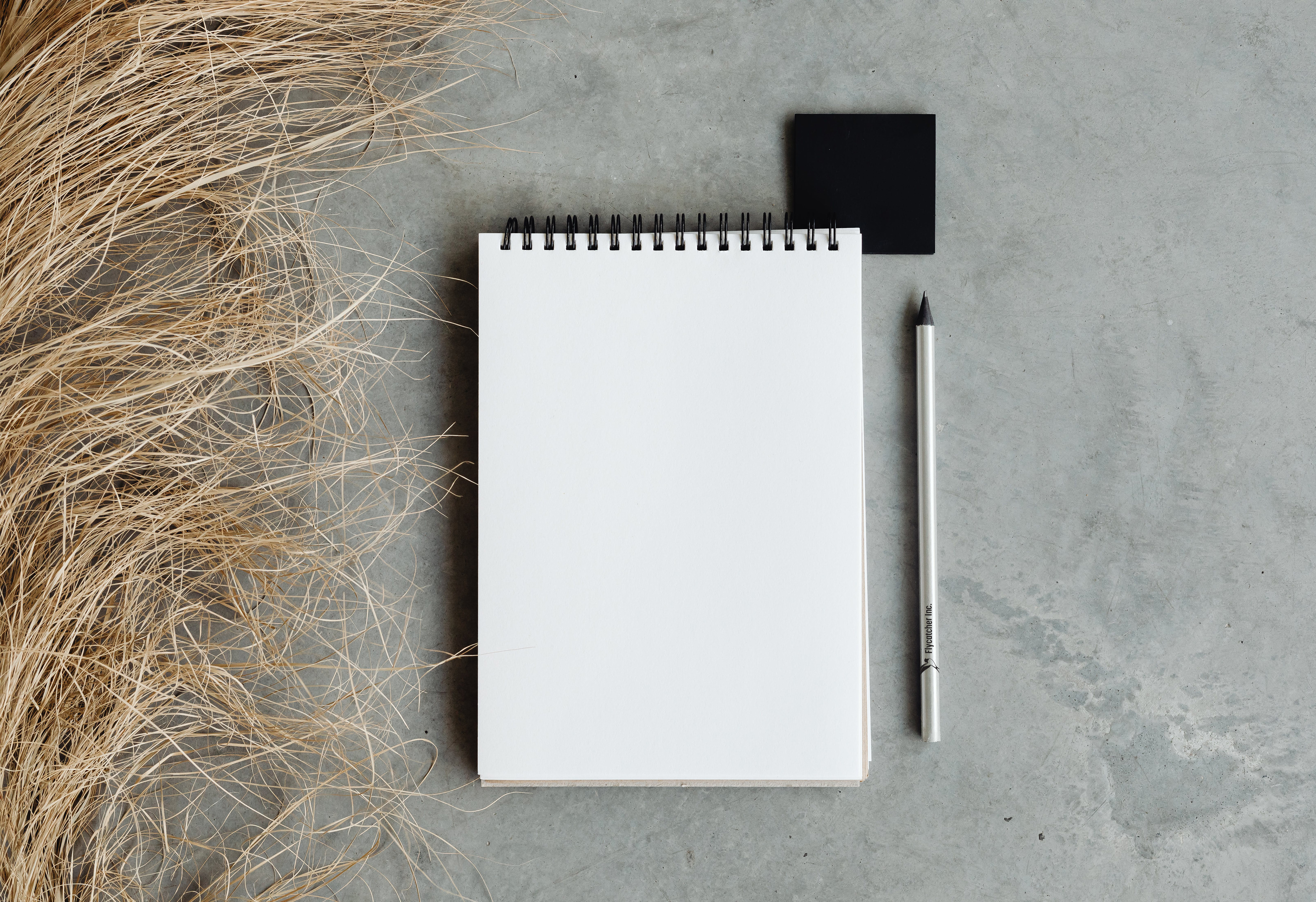 Pencil with custom-printed logo next to blank sketchpad