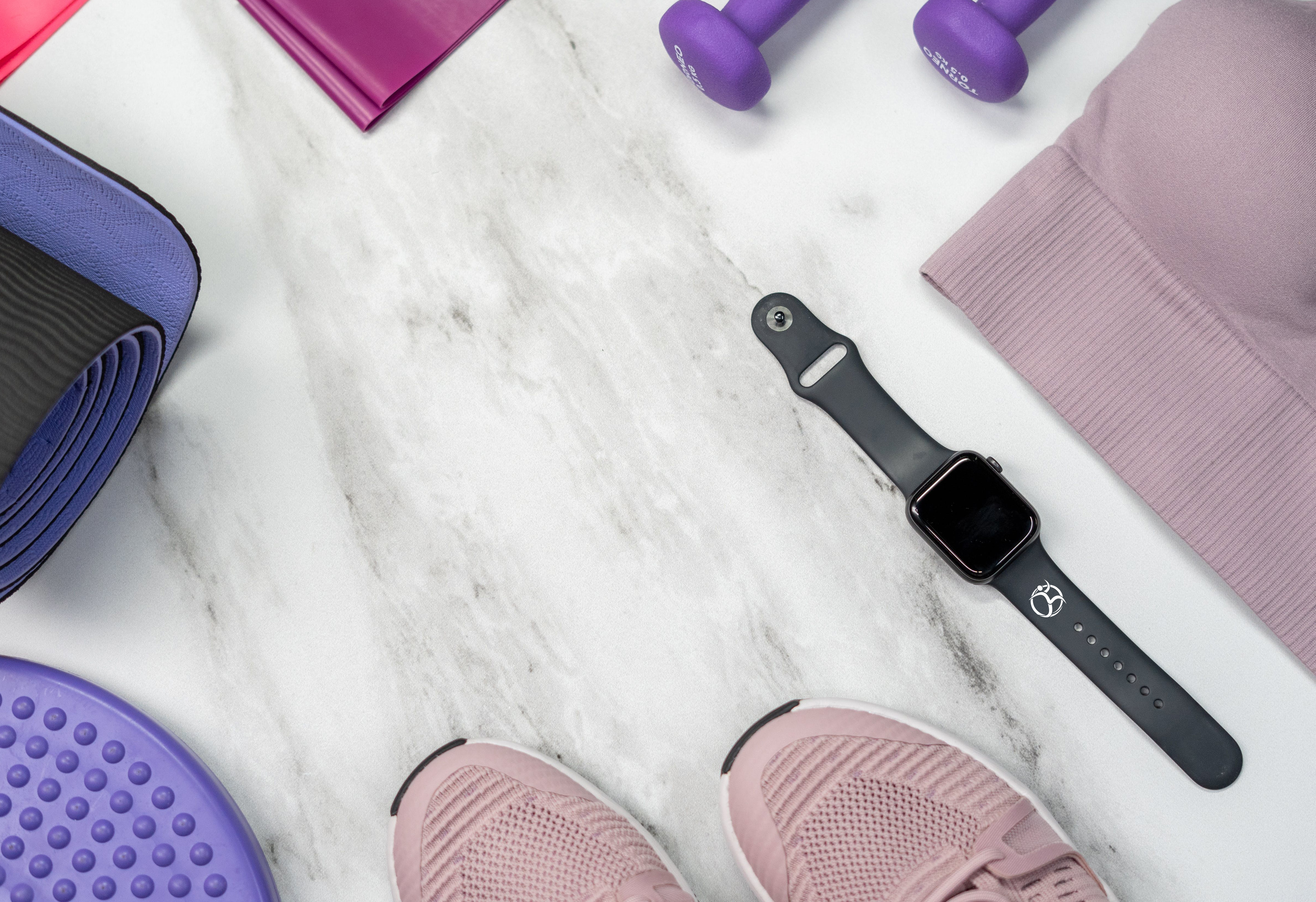 Touch screen watch with custom printed band next to various exercise equipment